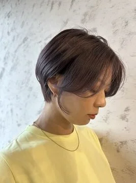 美容師がヘアケア剤を手に取り毛束になじませている様子